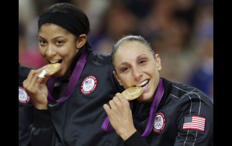 Diana Taurasi (D) y Candace Parker muerden sus medallas de oro durante la ceremonia. AP  /