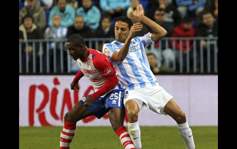 El delantero de Granada Odion Ighalo (i) lucha la posición del defensa del Málaga Weligton de Oliveira. EFE  /