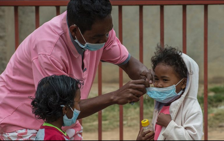 Un adulto protege  con mascarillas a dos menores en Antananarivo. El gobierno ha suspendido clases y comenzado la desinfección de las escuelas. AP/A. Joe
