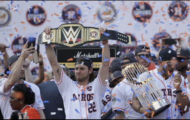 Josh Reddick levanta el cinturón y Carlos Correa sostiene el trofeo de la Serie Mundial.