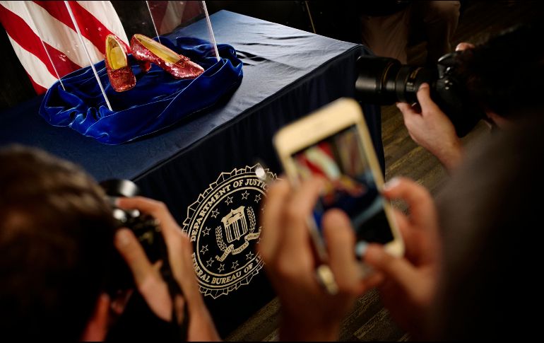 Varias personas toman fotografías de los zapatos recién encontrados. AP/R. Tsong-Taatarii