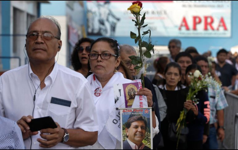 Una mujer con una foto del expresidente Alan Garía aguarda este viernes para entrar al local del partido donde se realiza el funeral en Lima, Perú. AP/M. Mejía