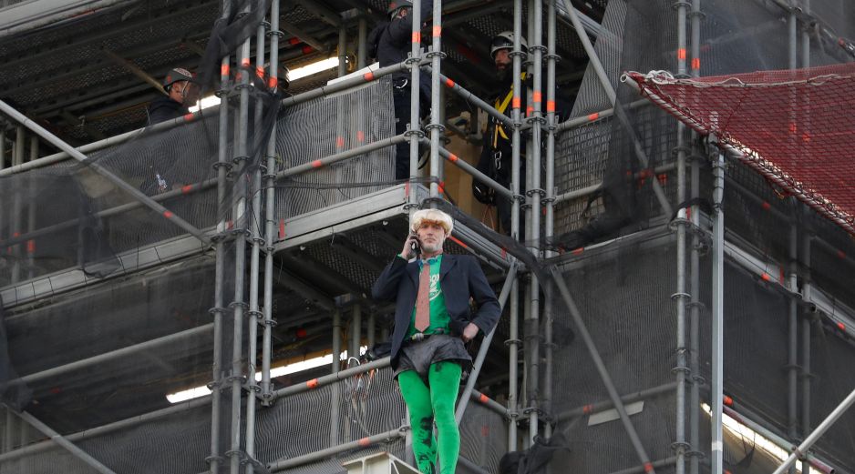 Tras subir sin protección por andamios instalados en Houses of Parliament, sede del parlamento británico, el militante disfrazado de Boris Johnson desplegó pancartas. AP/K. Wigglesworth