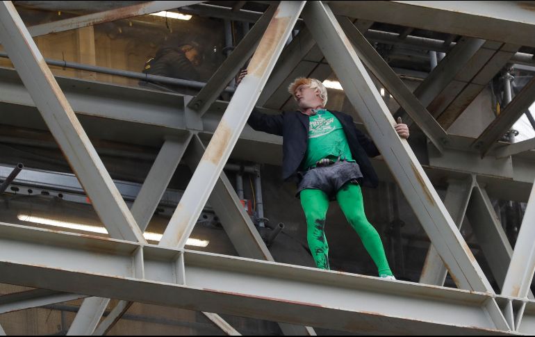Tras subir sin protección por andamios instalados en Houses of Parliament, sede del parlamento británico, el militante disfrazado de Boris Johnson desplegó pancartas. AP/K. Wigglesworth