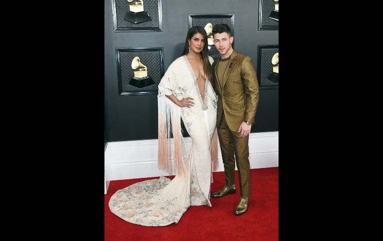 PAREJA DE ORO. Priyanka Chopra y Nick Jonas son una pareja  ardiente que además se demuestran el amor que viven a donde quiera que van y este resaltó en la alfombra roja. Ella luciendo un espectacular escote que en sinergia con unos llamativos flecos en las mangas le daban un aire muy sofisticado al vestido. Él, con un traje sastre en tono dorado que lo hacía verse muy glamoroso. AFP