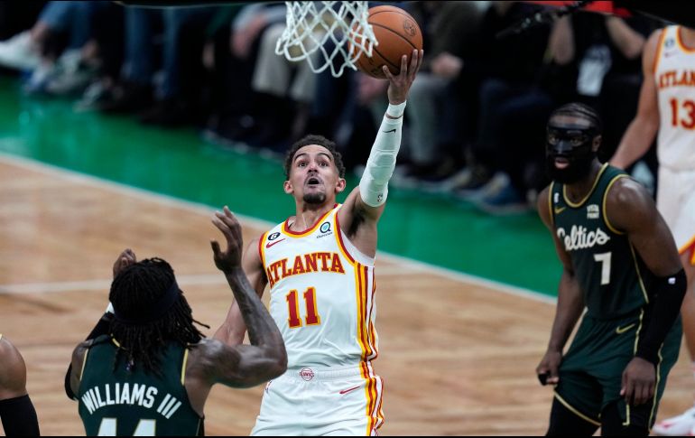 Trae Young esquiva la marca de Robert Williams III y Jaylen Brown. El guardia de Atlanta hizo 38 puntos anoche. AP/C. Krupa