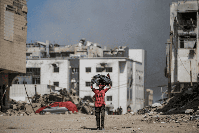 Un niño palestino camina mientras se eleva el humo tras un ataque aereo israelí cerca del hospital Al-Shifa en la ciudad de Gaza, Franja de Gaza, el 28 de septiembre de 2025. EFE / Mohammed Sabber