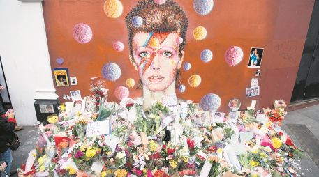 Ofrendas florales se acumularon bajo un mural de David Bowie, pintado por el artista urbano australiano James Cochran (Jimmy C), un día después de anunciarse su muerte, en Brixton, al sur de Londres. AFP