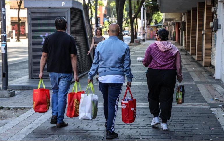 Seguir la rutina con reservas. Personas avanzan por las calles con bolsas de despensa en un lunes de alta tensión. EL INFORMADOR / A. Navarro