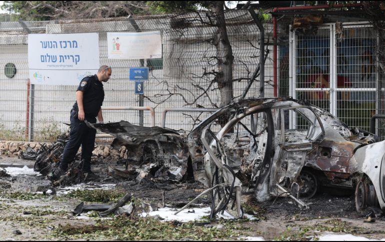 Un policía israelí inspecciona coches calcinados tras el impacto de fragmentos de un misil balístico iraní interceptado en Tel Aviv, Israel, el 15 de marzo de 2026. EFE/A. SULTAN