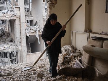 Una mujer trata de limpiar una vivienda en el barrio de Haft Chenar de Teherán que resultó dañada en un ataque de Estados Unidos e Israel. EFE/J. León