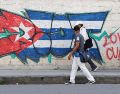 Personas caminan frente a un mural con la bandera de Cuba en La Habana. EFE/E. Mastrascusa
