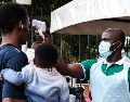 Un funcionario de salud utiliza un termómetro para tomar la temperatura a las personas frente al Hospital Musulmán de Kibuli, en Kampala, Uganda. AP/H. Nalwadda