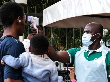 Un funcionario de salud utiliza un termómetro para tomar la temperatura a las personas frente al Hospital Musulmán de Kibuli, en Kampala, Uganda. AP/H. Nalwadda