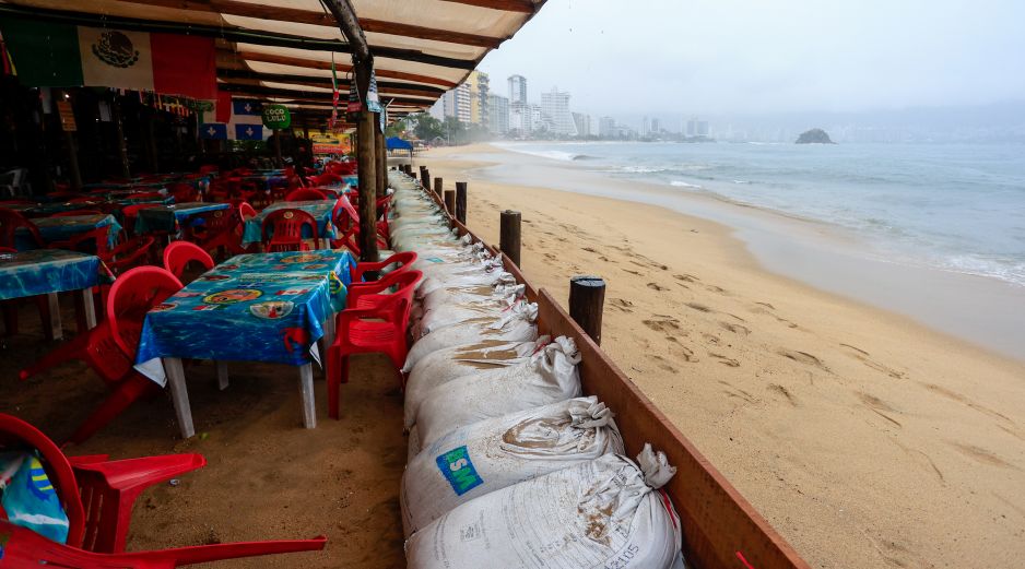 Personas protegen un negocio con costales pesados ante el pronóstico de fuertes lluvias este lunes, en Acapulco. EFE/D. Guzmán