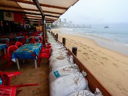 Personas protegen un negocio con costales pesados ante el pronóstico de fuertes lluvias este lunes, en Acapulco. EFE/D. Guzmán