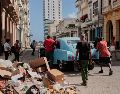 Varias personas empujan un coche clásico americano averiado junto a un montón de basura en La Habana. AP/J. Banos