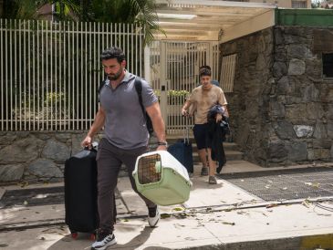 Personas salen de un edificio con pertenencias y mascotas este jueves, en el municipio Chacao en Caracas. EFE/B. Vergara