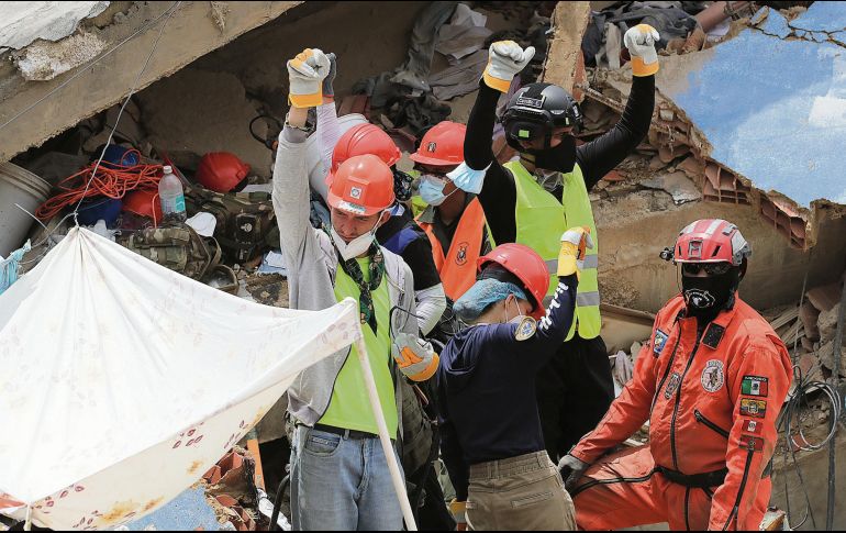 Rescatistas, entre ellos los Topos Azteca, piden silencio a los presentes tras haber escuchado sonidos bajo los escombros de un edificio. EFE