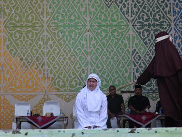 Una mujer de Aceh reacciona a los azotes durante un castigo público por violar la ley islámica en Banda Aceh, Indonesia, el 2 de julio de 2026. El Tribunal de la Sharia y la Fiscalía de Banda Aceh castigaron a los infractores con entre 10 y 30 azotes, incluyendo a una pareja que fue sorprendida besando a sus parejas en directo en la plataforma TikTok. EFE/H. SIMANJUNTAK