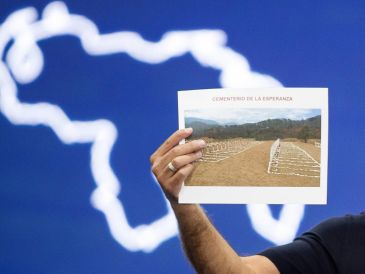 El presidente del Parlamento, Jorge Rodríguez, sostiene una imagen del cementerio La Esperanza durante una rueda de prensa este sábado. EFE/R. Peña