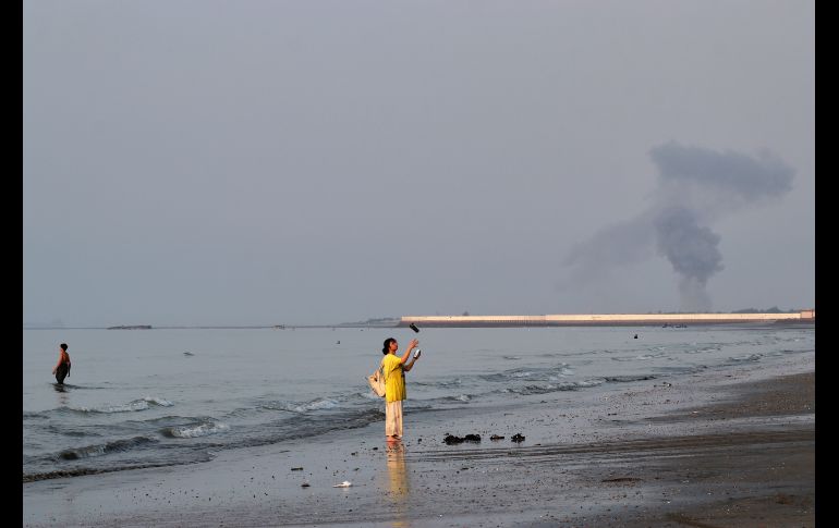 Una mujer cerca de la orilla del mar a lo largo del estrecho de Ormuz, mientras se levanta una columna de humo tras una explosión, frente a Bandar Abbas, Irán. AP/R. Poudat