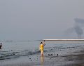 Una mujer cerca de la orilla del mar a lo largo del estrecho de Ormuz, mientras se levanta una columna de humo tras una explosión, frente a Bandar Abbas, Irán. AP/R. Poudat