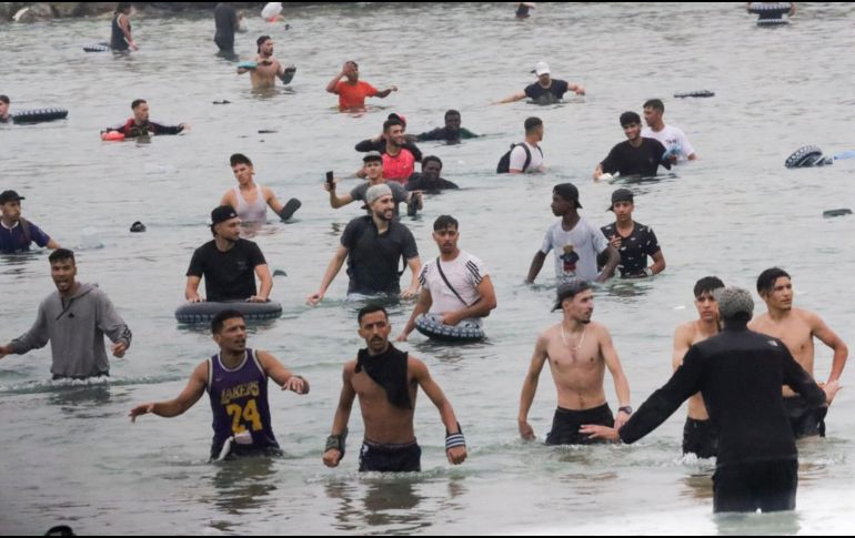 Un grupo de inmigrantes en la playa junto al paso fronterizo del Tarajal en Ceuta este viernes, donde se han registrado violentos enfrentamientos en los perímetros fronterizos durante su intento de acceder desde Marruecos hacia Ceuta y Melilla. EFE/ R. Dris