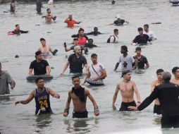 Un grupo de inmigrantes en la playa junto al paso fronterizo del Tarajal en Ceuta este viernes, donde se han registrado violentos enfrentamientos en los perímetros fronterizos durante su intento de acceder desde Marruecos hacia Ceuta y Melilla. EFE/ R. Dris