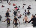 Un grupo de inmigrantes en la playa junto al paso fronterizo del Tarajal en Ceuta este viernes, donde se han registrado violentos enfrentamientos en los perímetros fronterizos durante su intento de acceder desde Marruecos hacia Ceuta y Melilla. EFE/ R. Dris