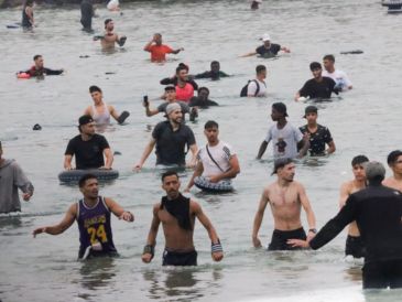 Un grupo de inmigrantes en la playa junto al paso fronterizo del Tarajal en Ceuta este viernes, donde se han registrado violentos enfrentamientos en los perímetros fronterizos durante su intento de acceder desde Marruecos hacia Ceuta y Melilla. EFE/ R. Dris