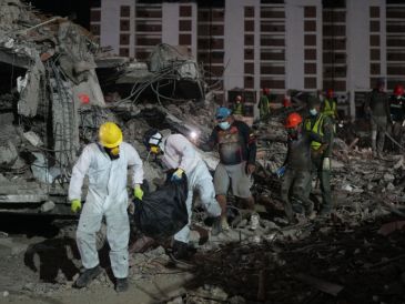 Unas personas transportan un cadáver rescatado de un edificio que se derrumbó a causa de los terremotos en La Guaira, Venezuela. AP/A. Cubillos