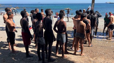 Jóvenes inmigrantes que duermen en la calle hacen fila para bañarse en la playa del Trampolín, tras acceder a Ceuta el pasado jueves. EFE/Reudan