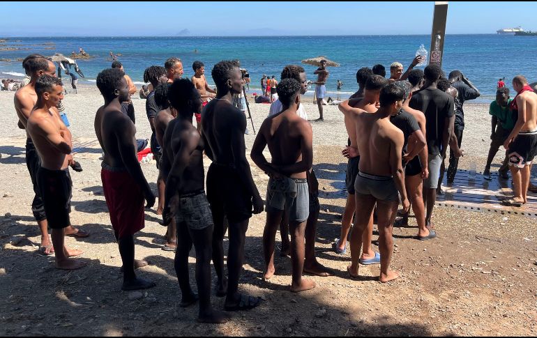Jóvenes inmigrantes que duermen en la calle hacen fila para bañarse en la playa del Trampolín, tras acceder a Ceuta el pasado jueves. EFE/Reudan