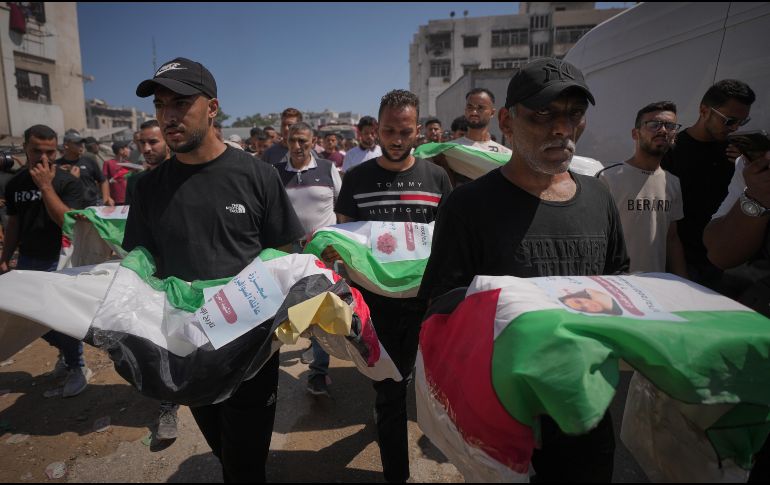 Dolientes cargan los cuerpos, cubiertos con banderas, de palestinos muertos en ataques israelíes durante la guerra contra Hamás, cuyos restos fueron recuperados recientemente de entre los escombros, en Ciudad de Gaza, el jueves 20 de agosto de 2026. Foto AP/J. Alshrafi