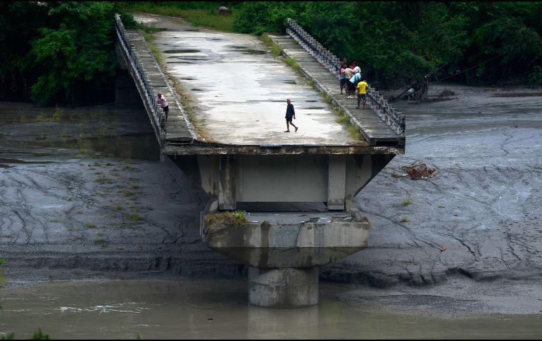 Un grupo de personas permanece sobre los restos de un puente que cruzaba el río Trishuli y fue arrastrado por una crecida repentina, en el distrito de Dhading, Nepal, el domingo 30 de agosto de 2026. AP/N. Shrestha
