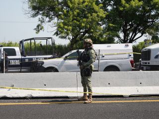 Un agente de la Policía Federal permanece junto a vehículos policiales cerca del lugar donde se halló el cuerpo del diputado Zenyazen Escobar García. AFP/V. Razo