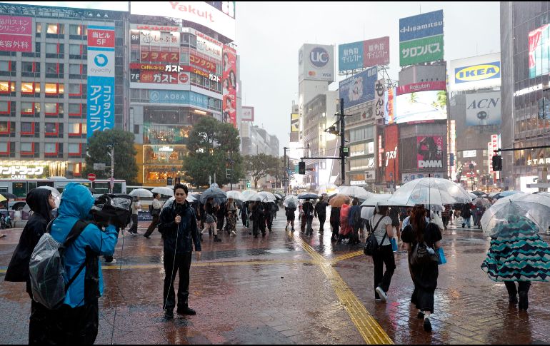 Un equipo de televisión realiza un reportaje cerca del cruce de Shibuya bajo las fuertes lluvias provocadas por el tifón Dujuan en Tokio, Japón, el 21 de septiembre de 2026. EFE/F. ROBICHON