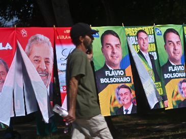 Un hombre camina frente a una tienda informal de banderas con la imagen del presidente de Brasil y candidato a la reelección, Luiz Inácio Lula da Silva, y del candidato presidencial, Flávio Bolsonaro. EFE/A. Borges