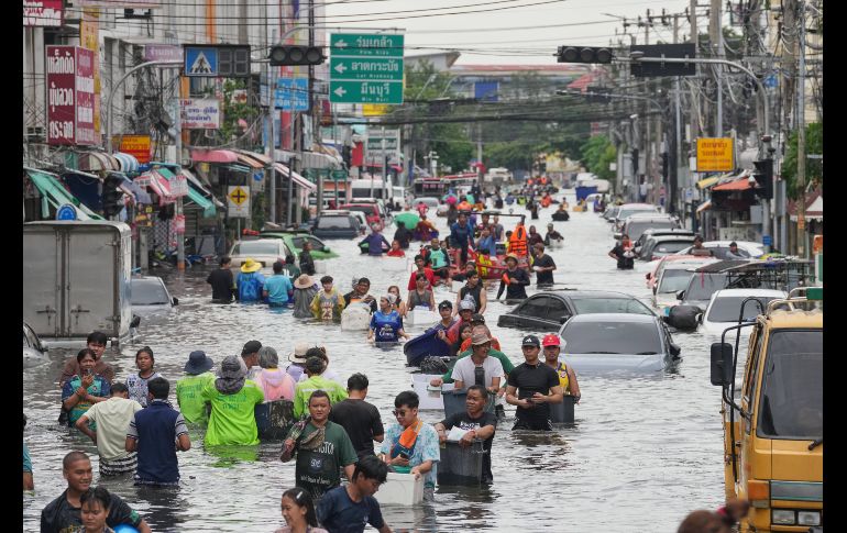 Personas caminan por una calle inundada tras fuertes lluvias en Bangkok, Tailandia. AP/S. Lalit