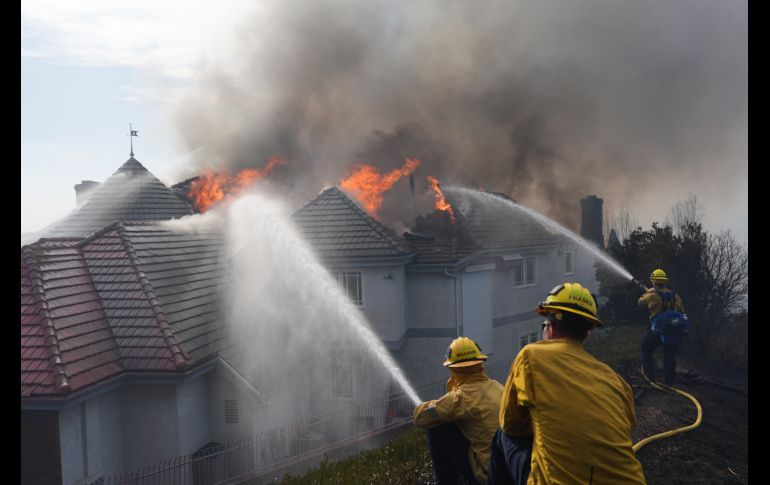 Bomberos trabajan para apagar fuego en una casa durante el incendio 