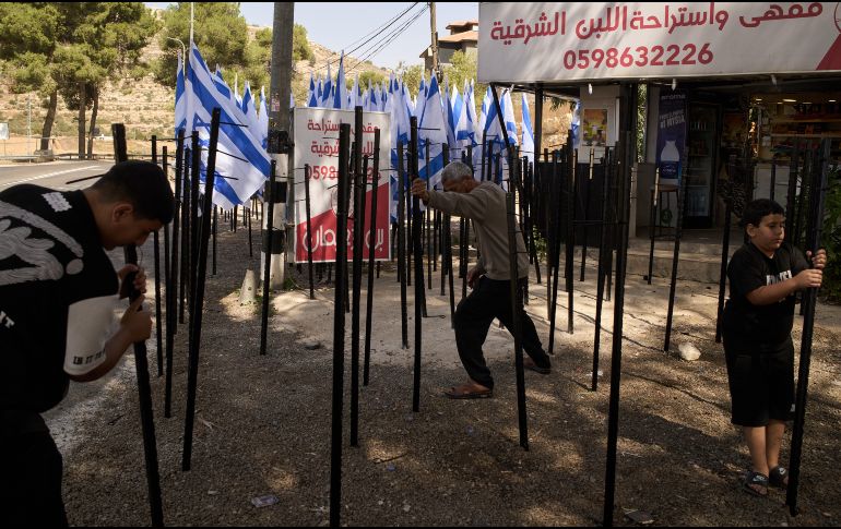 El palestino Mouayad Oweis y sus hijos tratan de retirar astas de bandera colocadas por colonos israelíes para bloquear el acceso a su cafetería en el poblado de al-Lubban al-Sharqiya, Cisjordania, el jueves 8 de octubre de 2026. AP/ Leo Correa
