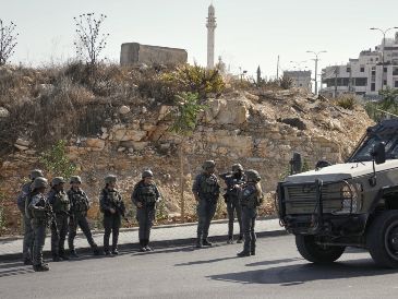 Soldados israelíes se reúnen en el lugar de un ataque a tiros perpetrado por hombres armados palestinos en un cruce cerca de Hebrón, en la Cisjordania ocupada. AP/M. Illean